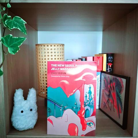 Livre The New Seoul Park Jelly Massacre par Cho Ye-eun dans une case de kallax avec des livres, une petite lampe et une peluche mini totoro blanche en arrière plan