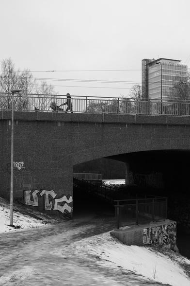 A photo of a bridge. There is a person with a pram on it.