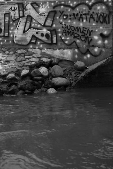 A photo of graffiti in the background and running water in the foreground.