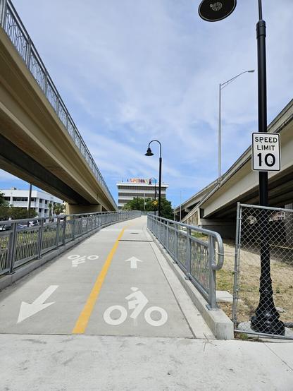 Entrance to new pedestrian Bridge.  Marking lanes for "traffic" direction and speed limit (for bikes) of 10 mph.