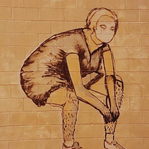 Mural of a woman putting on leg warmers.