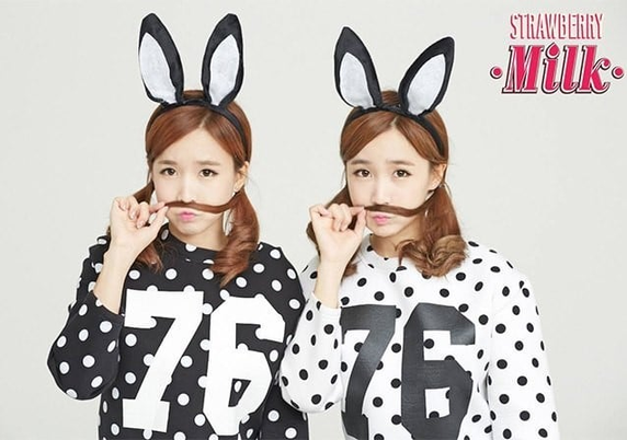 Twin sisters from Crayon Pop. They are wearing matching black bunny ears and black and white polka-dot jerseys with 76 on them. The jerseys are color inverse of each other. They are both doing that "hold your hair like a mustache" thing that I think is unfairly cute.