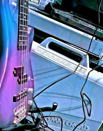 An over-saturated and colour shifted photograph of a bass guitar, Omnichord case, circuit-bent drum machine, and minidisc player box