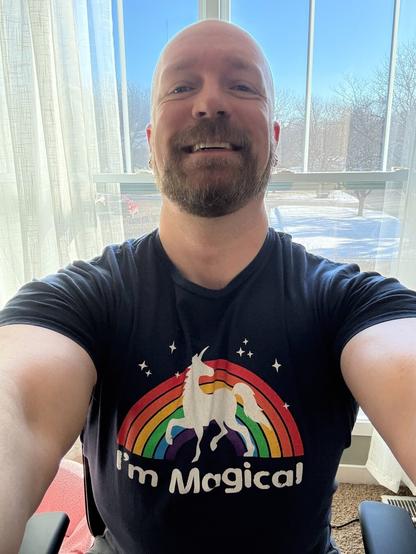 Pic of me, bald and bearded, in a navy tee with a uniform and rainbow on it that says “I’m Magical.” I’m smiling. It’s cold out.
