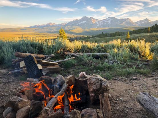 A campfire with the Sawtooth Mountains in the background
