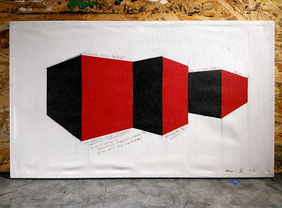 Ein rechteckiges abstraktes Gemälde steht auf einem Tisch mit Metalloberfläche, angelehnt an eine Holzplatte aus OSB-Material. Das Bild zeigt nebeneinander drei kubische Strukturen in Schwarz und Rot auf weißem Hintergrund, darum herum mit Tusche geschrieben Zeilen aus einem Gedicht.
