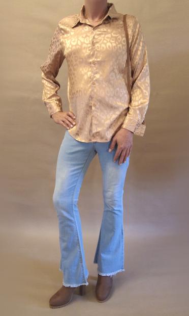 Me seen from the front wearing a gold leopard pattern blouse, bell bottom jeans, high heeled brown chelsea boots and carrying a small clutch in a shoulder strap.