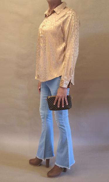 Me seen from my left wearing a gold leopard pattern blouse, bell bottom jeans, high heeled brown chelsea boots and carrying a small clutch in my left hand.