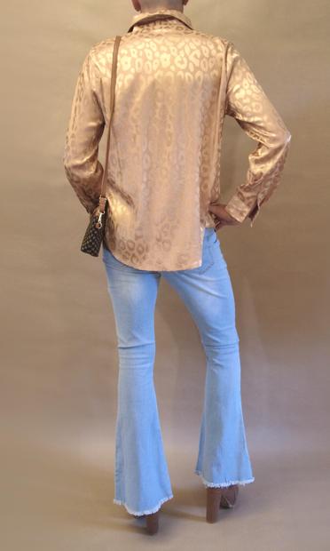 Me seen from the rear wearing a gold leopard pattern blouse, bell bottom jeans, high heeled brown chelsea boots and carrying a small matching clutch in a shoulder strap.