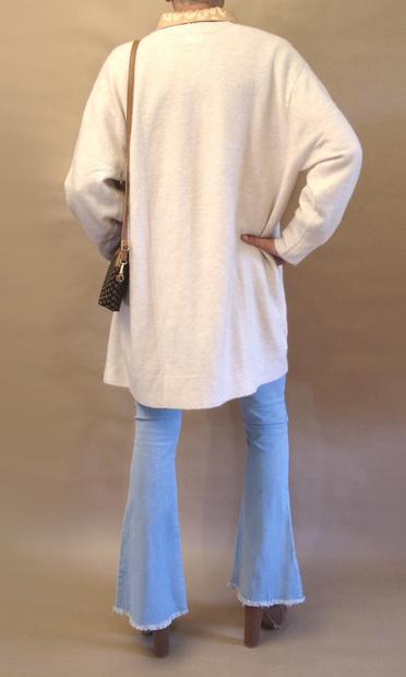 Me seen from the rear wearing a gold leopard pattern blouse and a long beige cardigan, bell bottom jeans, high heeled brown chelsea boots and carrying a small clutch in a shoulder strap.