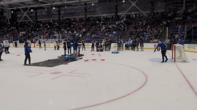 3 robots on the ice in between periods of a hockey game.