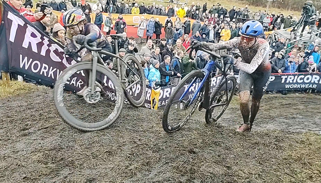 Two cyclocrossers pushing their bikes up a ramp