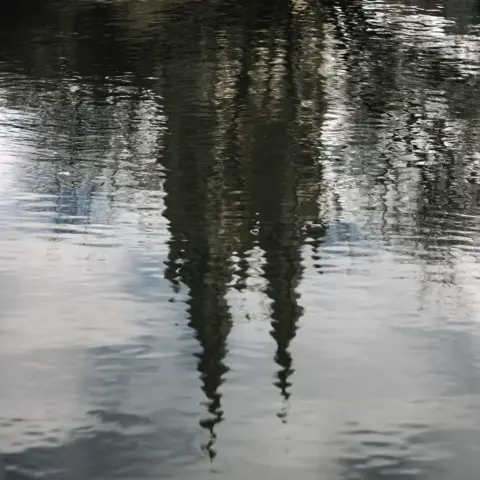 Reflet d’une église à deux cloché dans de l’eau ondulée