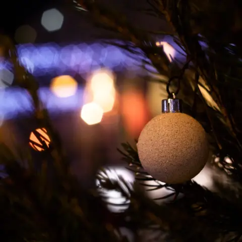 Focus sur une boule de noel sur un sapin, le fond est flou avec des bokeh hexagonaux de petites lumières