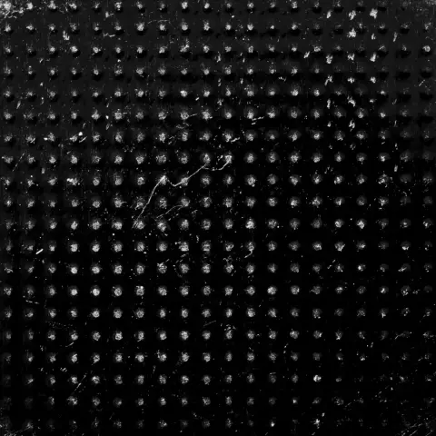 Photo macro d’une pile plate, on y voit un quadtillage de maiques d’usure gris claire sur un fond gris foncé.
