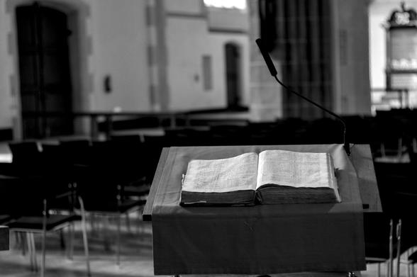 A black and white photo of the interior of a church in Groningen, Netherlands. In the bottom right hand corner an ambo with an open Bible.

Ein Schwarz-Weiß-Foto des Innenraums einer Kirche in Groningen, Niederlande. In der rechten unteren Ecke ein Pult mit einer aufgeschlagenen Bibel.