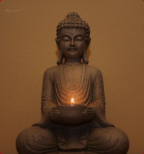 Das Bild zeigt einen Buddha mit einer Schale in seinen Händen, in der eine Kerze brennt. Das Bild vermittelt eine ruhige, meditative Stimmung.