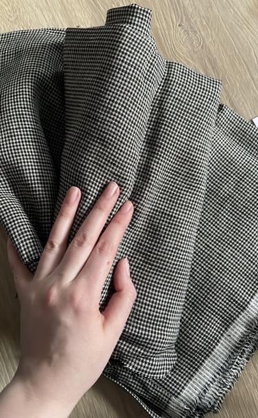 my hand resting on a pile of linen black and neutral colored checked linen