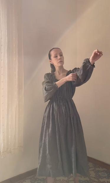 Jessica Silversaga in her new dress design. A long sleeved dress with ruffles around the neckline and wrist cuffs and a draw string for waist definition. The dress is midi lenght and she stand in a sunlight dress