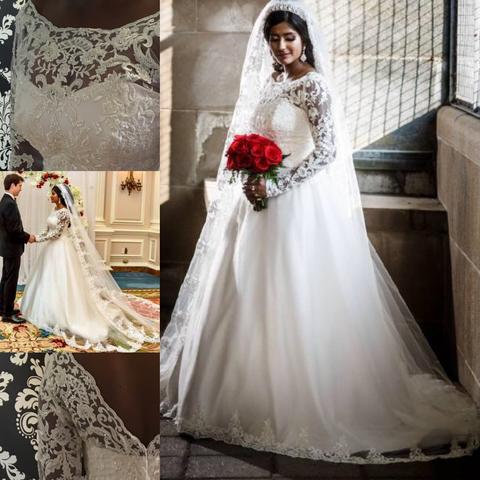 Collage showing wedding dress and details:
Upper left: lace over strapless bodice showing skin through upper chest into sleeves with scallop trim.
Mid-left:
Bride and groom full body image showing lace trimmed veil to the floor over full ball gown dress with matching lace trimmed veil to on skirt hem.
Bottom left: lace over strapless bodice showing upper back “v” opening and skin visible through to sleeves.
Main image on right: full view of ballgown showing full length lace sleeves and full length full skirt with scallops hand sewn to hem of skirt and veil.
South Asian bride in white dress.
