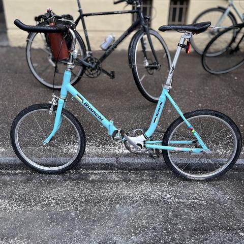 Ein hellblaues Klapprad mit Bianchi-Schriftzügen und sportlichem Lenker und Sattel.