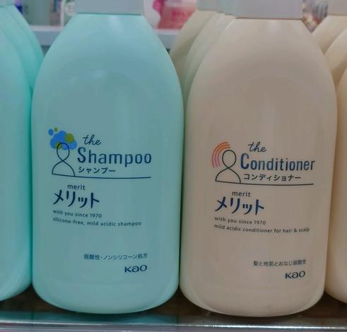 The image features two bottles of hair care products: a light blue bottle labeled "the Shampoo" and a cream-colored bottle labeled "the Conditioner." Both are branded as "merit" by Kao, highlighting their silicone-free and mild acidic formulas.