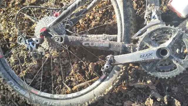 Ein Mountainbike liegt auf einem Waldweg. Zu sehen ist der Antrieb, bei dem die Kette fehlt.