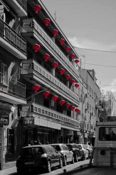 A typical spanish building in Usera district in Madrid, decorated with chinese lamps in red. The shot is in black and white.