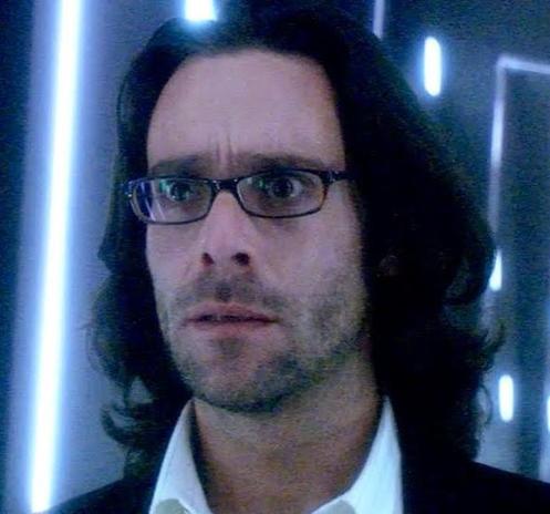 A man with black hair, wearing squarish glasses with dark frames.