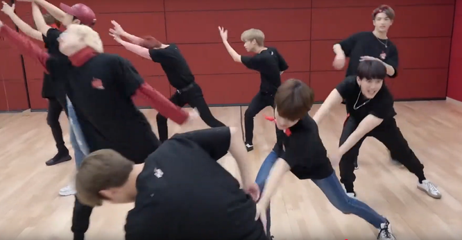 Skz in a dance practice studio. Lee Know is bending down in the front. Behind him Seungmin has a hand on his butt. Behind Seungmin, Changbin has both hands on Seungmin's butt.