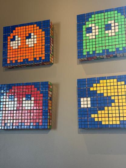 A photo I took of Pac-Man and three ghosts hanging on the wall at the local Red Robin. They appear to be made out of tile in some form. Pac-Man is yellow, then there is a red an orange and a green ghost.