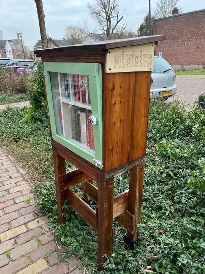 Wooden Little free library with a green door and a sign