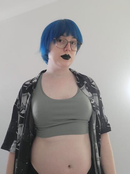Photo of Revy wearing black lipstick and glasses.
She's wearing a sports bra and a 2pac shirt.
You can see her cute tummy