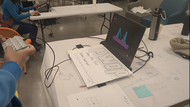 A laptop running PWOP has the keyboard covered with a hand-drawn PWOP sign. It's connected to a phone-sized box with 18 translucent plastic bubbles on top reminiscent of bubble wrap.