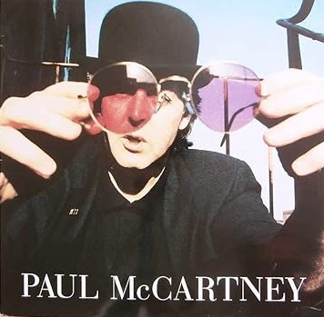 Sleeve art for Paul McCartney's "My Brave Face" single. Paul wears a bowler hat and looks into the camera while about to put a pair of round lens shades on it.