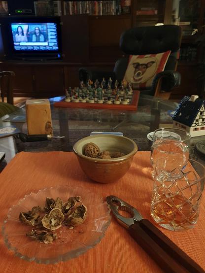 Glass of single malt and walnuts in the foreground with Bloomberg TV running in the background