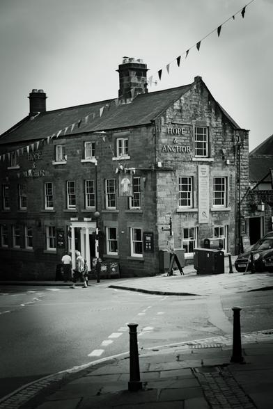 A pub called Hope and Anchor with festive bunting and some people at the front door.