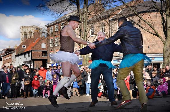 A street entertainer pictured persuading a couple of visitors to York in North East England to indulge in a merry dance in King's Square.