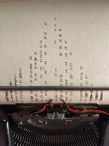 An image of a page rolling out of the typewriter with the text “falling back into place“. The letters of the sentence quite literally fall back into place as the letters are repeated from the top until the bottom. At the top you can sometimes read a loose letter B or K or a T, at the bottom the full sentence completes. Just below the text there’s a black typewriter and a ribbon with a black and red side together with metal structure of the typewriter.