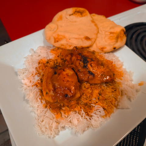 butter chicken over rice with naan bread