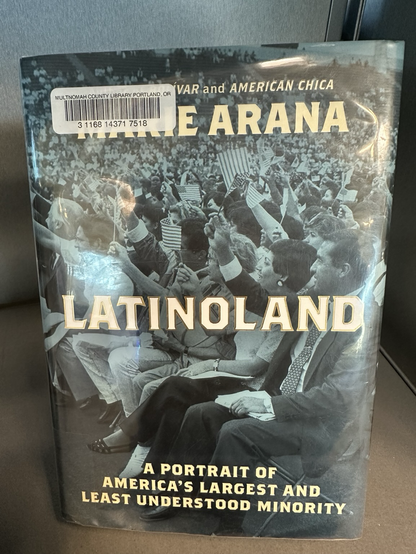 A book entitled “Latinoland: A portrait of Americans Largest and Least Understood Minority” by Marie Ariana. It is displayed prominently on a library bookshelf.