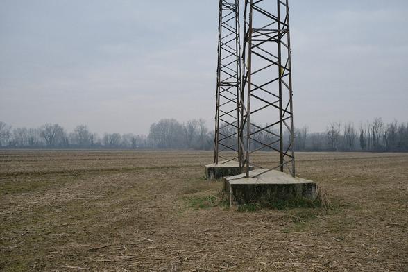Two transmission towers in a bare field, overcast sky in the background