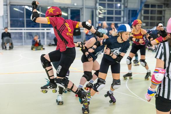 A color photo of a jamming person from Roller Derby Belgium doing an apex jump