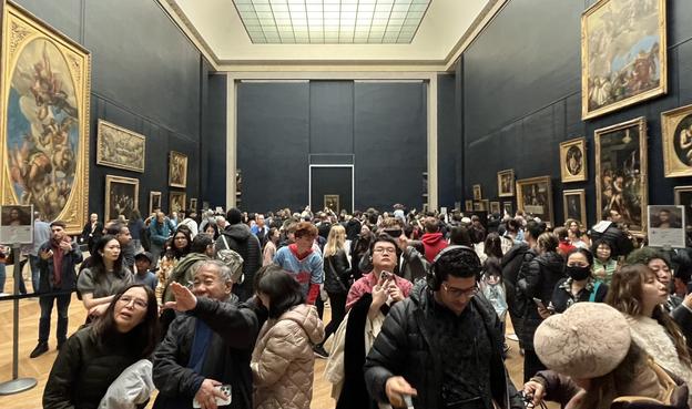 Exhibition room at The Louvre with the tiny Mona Lisa painting all the way back behind a horrifying horde of tourists.