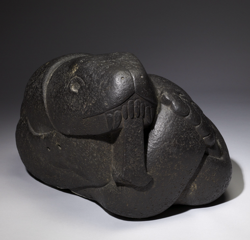 official museum photo of the object on gradient grey background, front profile view showing head. “Compact and smoothly polished, this rattlesnake displays typical Aztec sculptural techniques. Both the musculature of this snake's body and its head have been sculpted in great detail. The eyes were probably once inlaid, and ferocious fangs descend from the snake's upper jaw. Snakes were powerful symbols throughout Mesoamerican history, linked with the sky, rain, and agriculture. Aztecs may have seen the snake's shedding of its skin as a metaphor for the cyclical nature of life, death, and rebirth.”