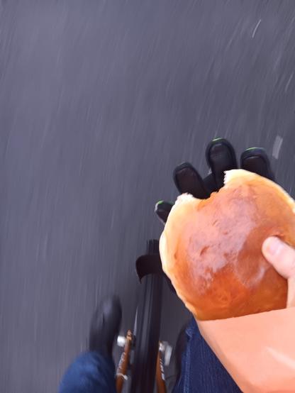 A chocolate bun held in one hand. Below you can see the wheel of a unicycle.