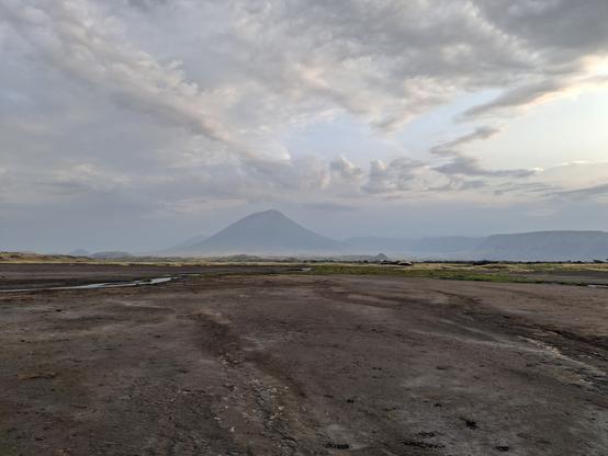 A view of the volcano, Ol Doinyo Lengai, which is a barmy looking conical volcano as drawn by a child, rising above the sands and mud flats on the shore of Lake Natron.
