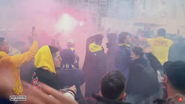 Photo of Maccabi Tel Aviv supporters on Dam Square with a lot of yellow clothing (club colors are yellow and blue) and burning torches