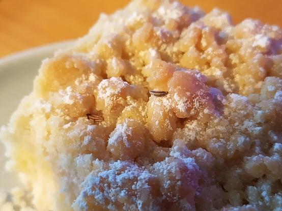 Ein Stück Streuselkuchen mit zwei einzelnen Kümmelkörnen