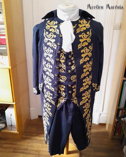 Costume pour GN (jeu de rôle grandeur nature). D'inspiration XVIIe siècle, il est bleu foncé avec plein de décorations dorées. Il est composé d'une chemise, d'une culotte à pont, d'un col à jabot, d'une gilet, d'un manteau et d'une ceinture